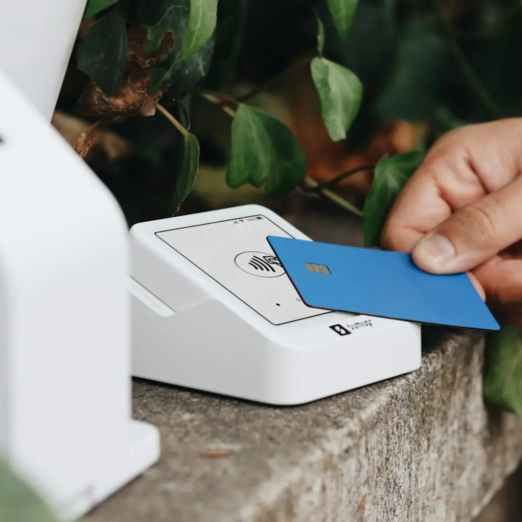 A person holding a credit card next to a machine